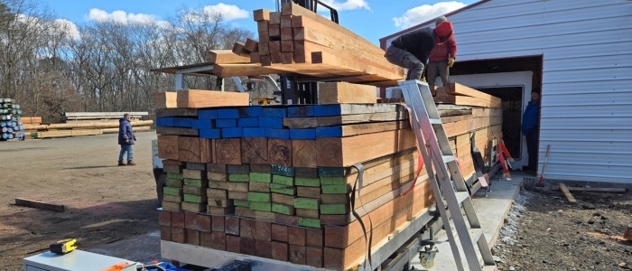 Worker stacking lumber with spacers inside a kiln for even drying process